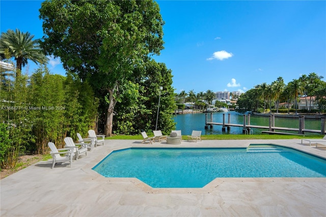 view of swimming pool with a patio area, a water view, and a dock