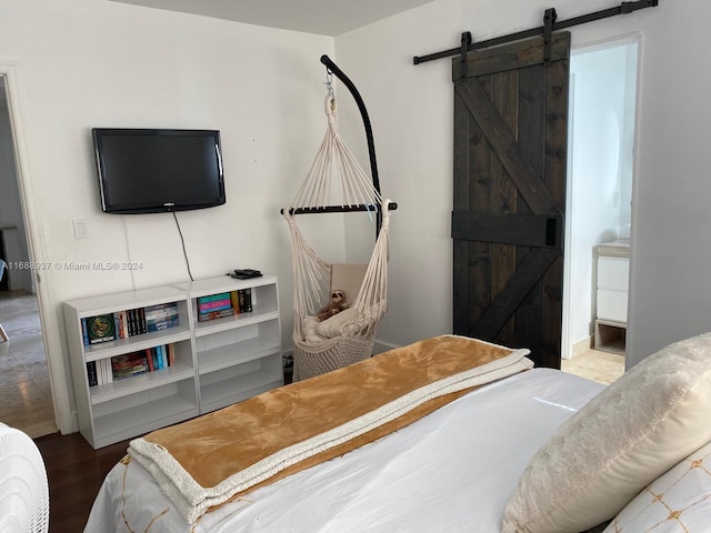 bedroom with connected bathroom, a barn door, and wood-type flooring