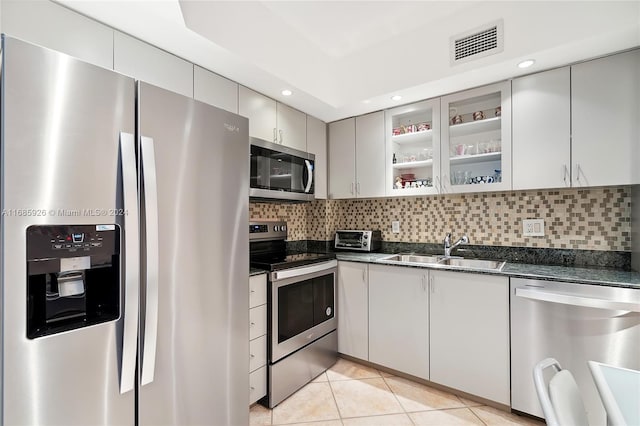 kitchen featuring stainless steel appliances, sink, tasteful backsplash, light tile patterned floors, and gray cabinets