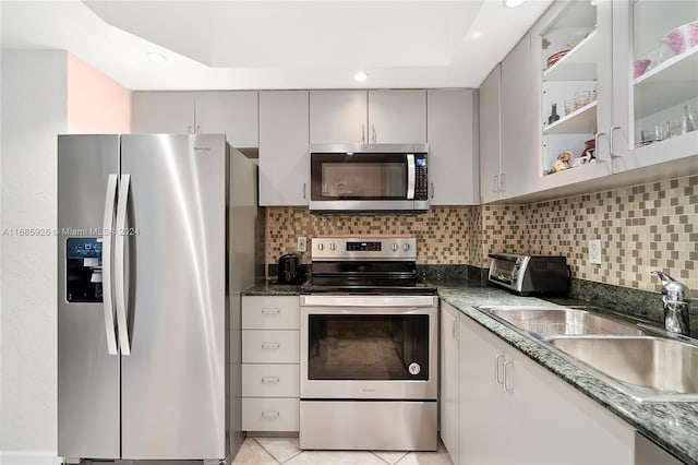 kitchen featuring stainless steel appliances, sink, tasteful backsplash, light tile patterned floors, and gray cabinetry