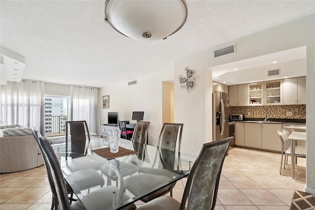 dining area featuring sink, a textured ceiling, and light tile patterned floors