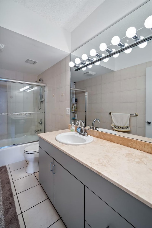 full bathroom with tile patterned floors, enclosed tub / shower combo, vanity, a textured ceiling, and toilet