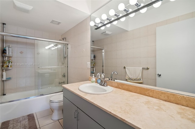 full bathroom with tile patterned flooring, enclosed tub / shower combo, vanity, toilet, and tile walls