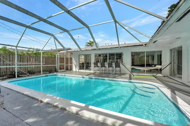 view of pool with glass enclosure, an outdoor bar, and a patio