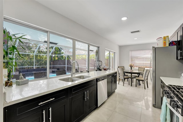 kitchen featuring light stone counters, sink, light tile patterned floors, and stainless steel appliances