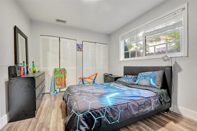 bedroom with light hardwood / wood-style flooring and two closets