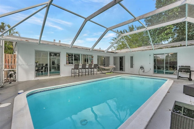 view of swimming pool with exterior bar, a patio, and a lanai