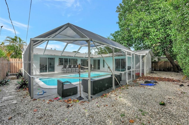 rear view of house with glass enclosure and a fenced in pool