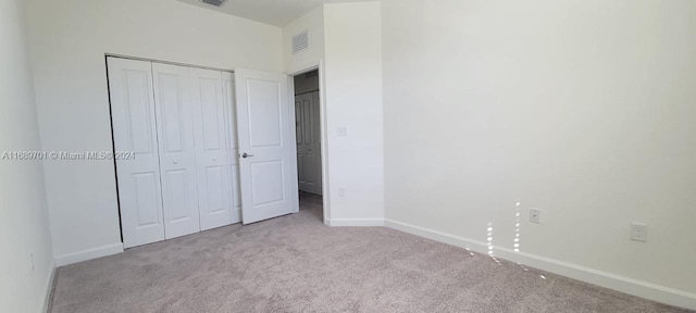 unfurnished bedroom with a closet and light colored carpet