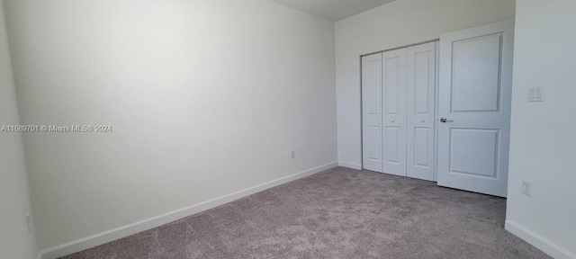 unfurnished bedroom featuring light colored carpet and a closet