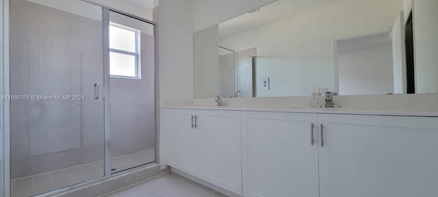 bathroom with a shower with door, vanity, and tile patterned floors