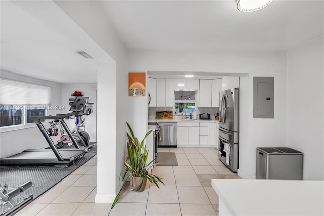 kitchen with appliances with stainless steel finishes, light tile patterned flooring, white cabinetry, and electric panel