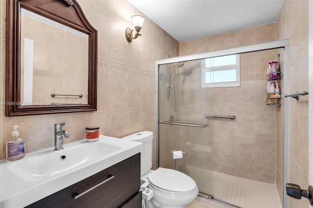 bathroom featuring toilet, vanity, tile walls, backsplash, and a shower with door