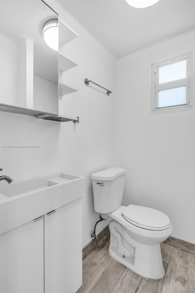 bathroom with hardwood / wood-style flooring, toilet, and vanity