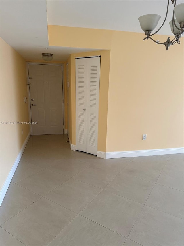 tiled empty room featuring a chandelier