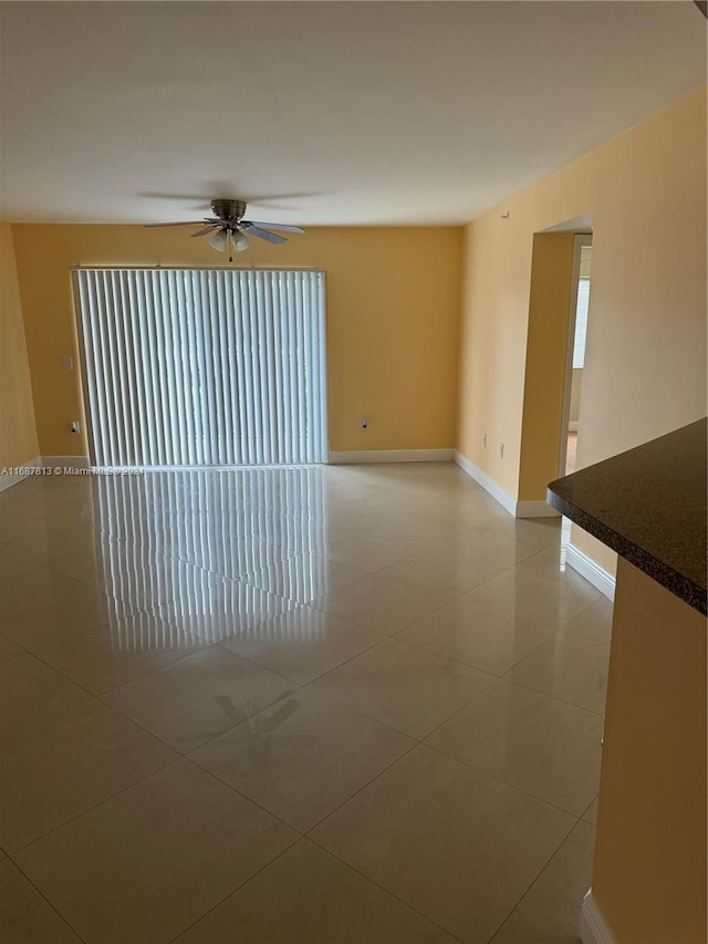 tiled spare room with ceiling fan