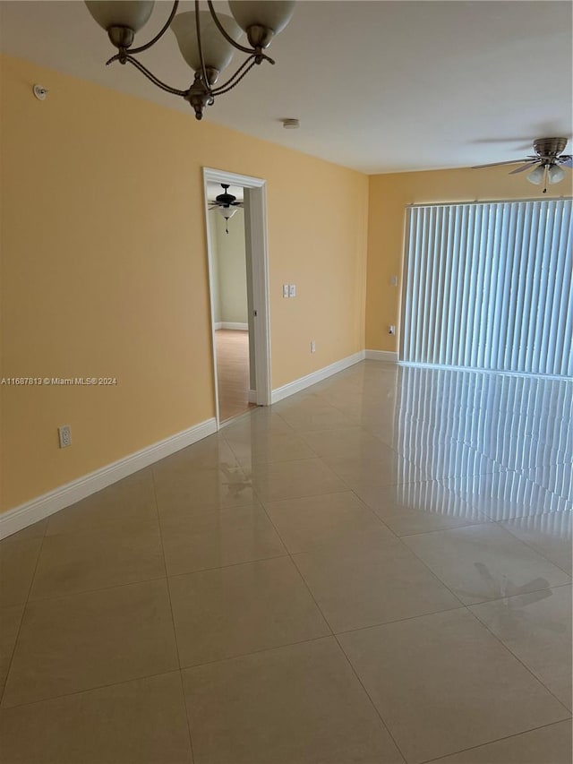 unfurnished room with ceiling fan with notable chandelier and light tile patterned floors