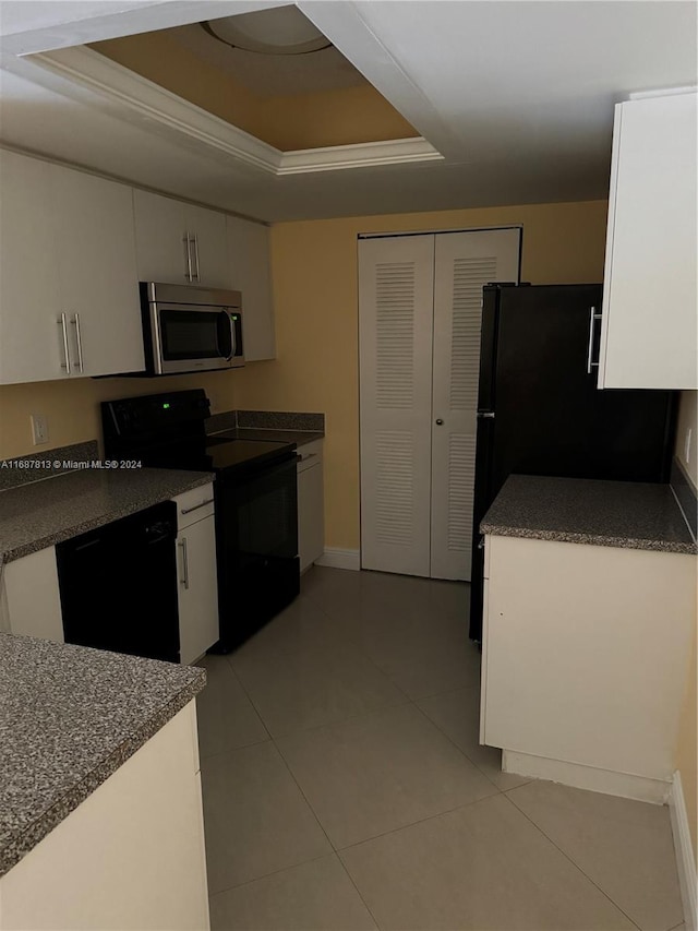 kitchen featuring white cabinetry, a raised ceiling, black appliances, and ornamental molding