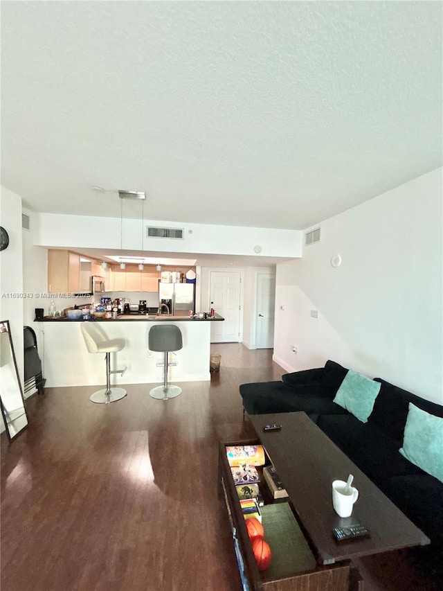 living room featuring a textured ceiling and dark hardwood / wood-style floors