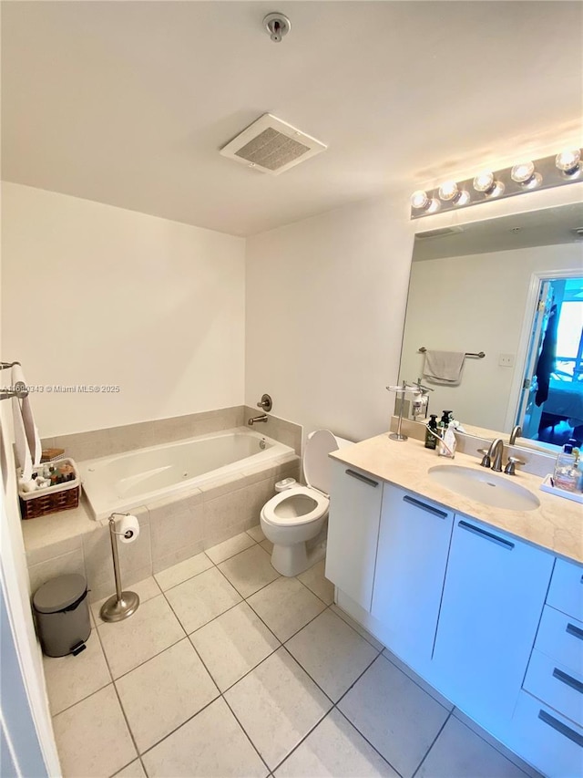 bathroom with tile patterned floors, vanity, a relaxing tiled tub, and toilet