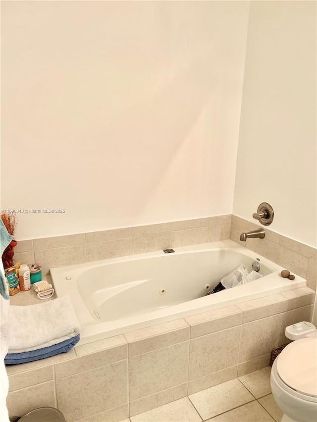 bathroom featuring tiled tub, tile patterned flooring, and toilet