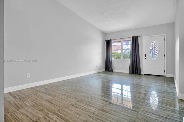 foyer with lofted ceiling, a textured ceiling, and tile patterned floors