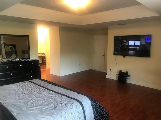 bedroom with hardwood / wood-style floors and a tray ceiling