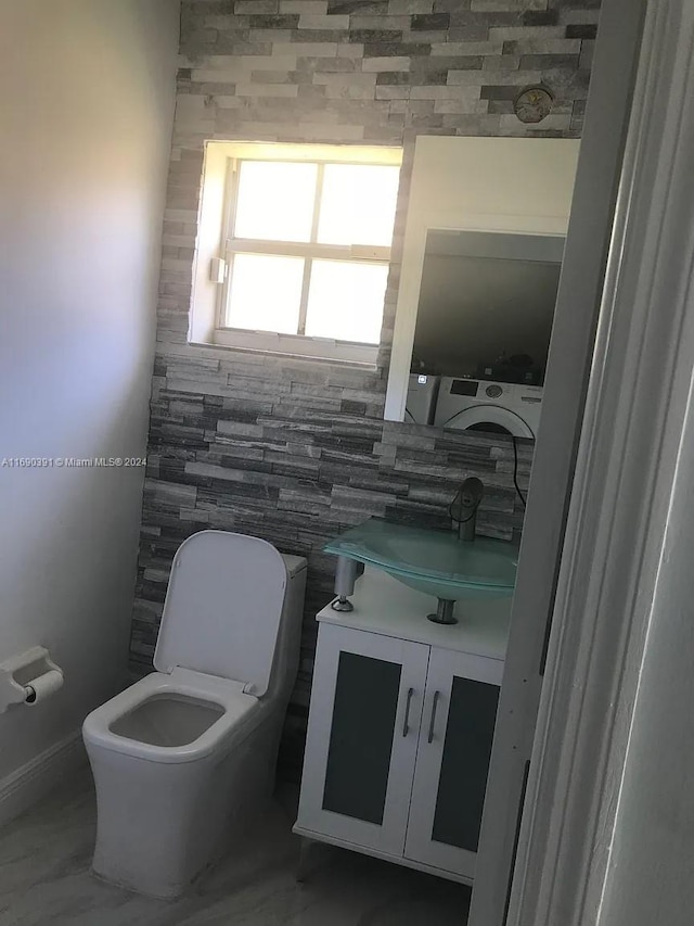 bathroom with toilet, vanity, and washer / dryer