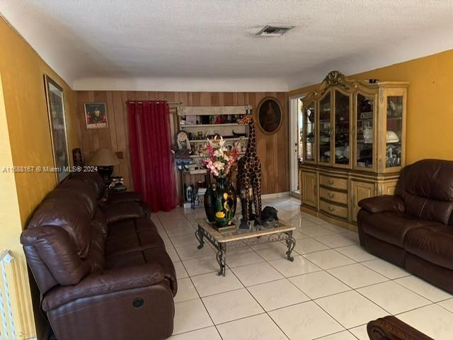 4325 NW 27th St, Lauderhill, FL 33313 - living area featuring light tile patterned flooring, wooden walls, and a textured ceiling