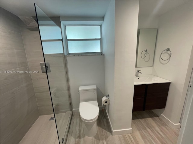 bathroom with toilet, vanity, hardwood / wood-style floors, and a tile shower