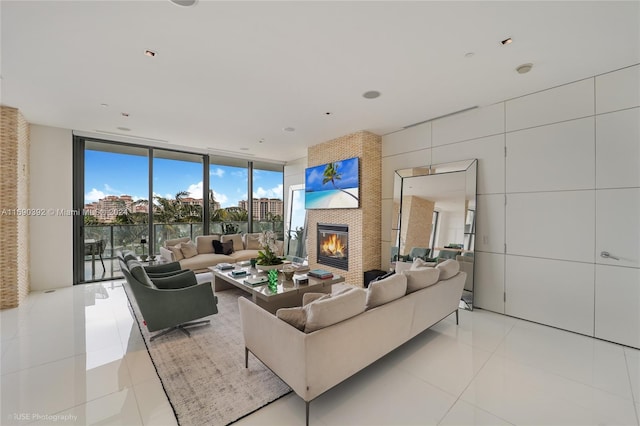 living room featuring a wall of windows, light tile patterned floors, and a large fireplace