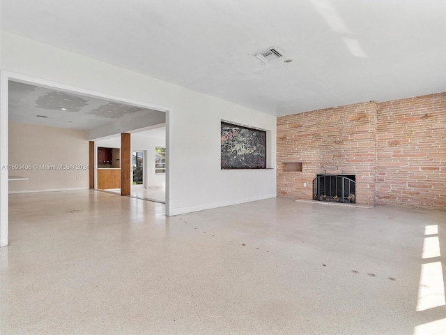 unfurnished living room featuring a fireplace and brick wall