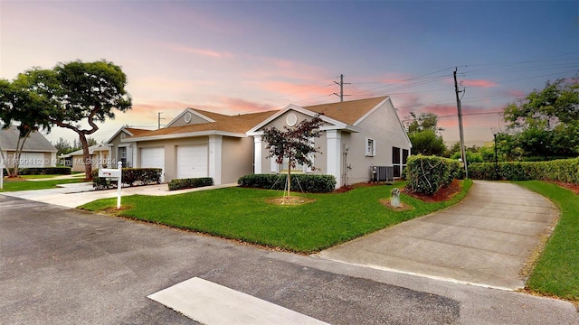 view of front facade featuring a garage, cooling unit, and a lawn