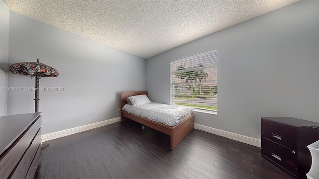 bedroom featuring dark hardwood / wood-style flooring and a textured ceiling