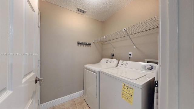 laundry area with a textured ceiling, light tile patterned floors, and independent washer and dryer