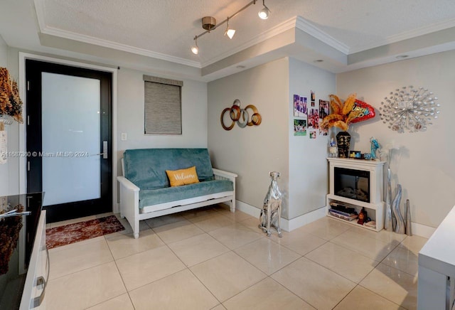 living area with a textured ceiling, crown molding, a tray ceiling, and light tile patterned flooring