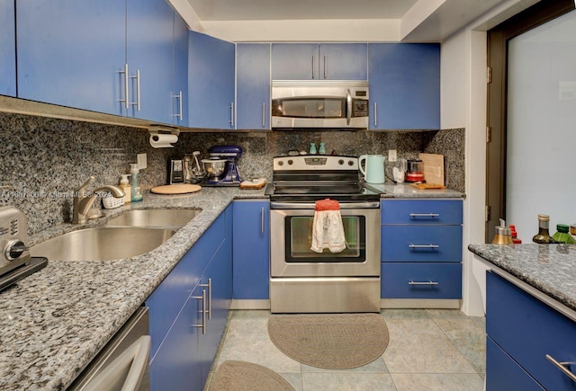 kitchen with stainless steel appliances, light stone counters, blue cabinets, light tile patterned floors, and sink