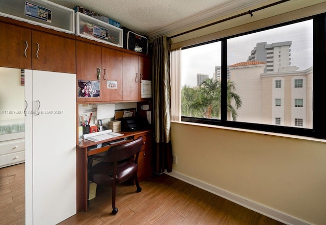 office area with light hardwood / wood-style flooring, a textured ceiling, and built in desk