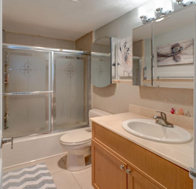 full bathroom featuring tile patterned flooring, enclosed tub / shower combo, toilet, and vanity