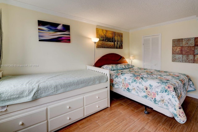 bedroom featuring ornamental molding, light hardwood / wood-style floors, a textured ceiling, and a closet