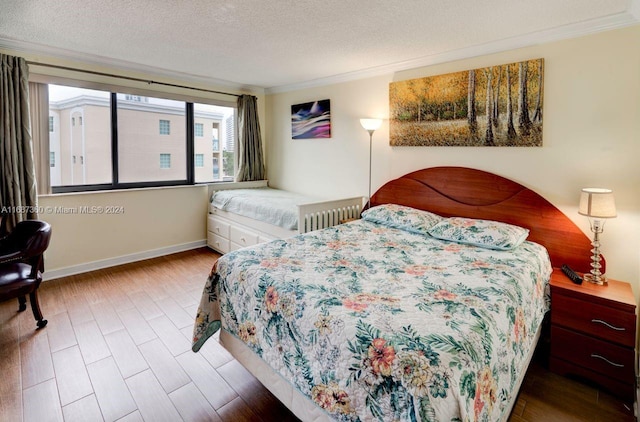 bedroom featuring hardwood / wood-style flooring, a textured ceiling, and ornamental molding