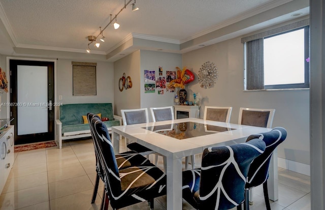 dining room with a textured ceiling, ornamental molding, and a raised ceiling