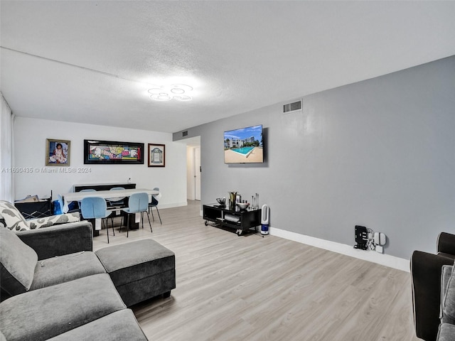 living room with light hardwood / wood-style floors and a textured ceiling