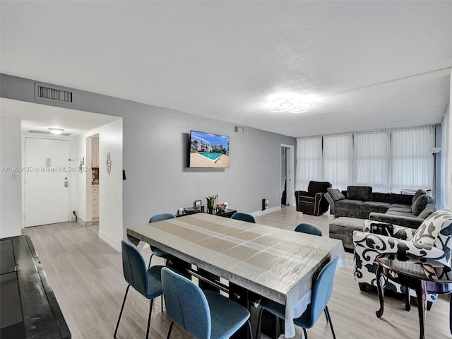 dining room with a textured ceiling and light hardwood / wood-style flooring