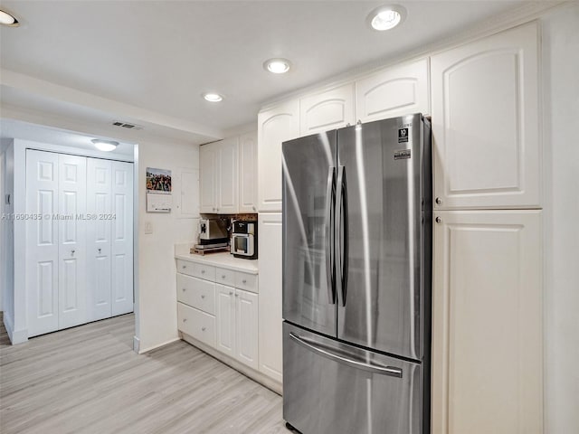 kitchen featuring stainless steel refrigerator, light hardwood / wood-style floors, and white cabinets