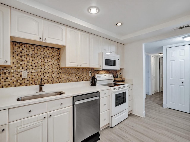 kitchen with white cabinets, white appliances, light wood-type flooring, and tasteful backsplash