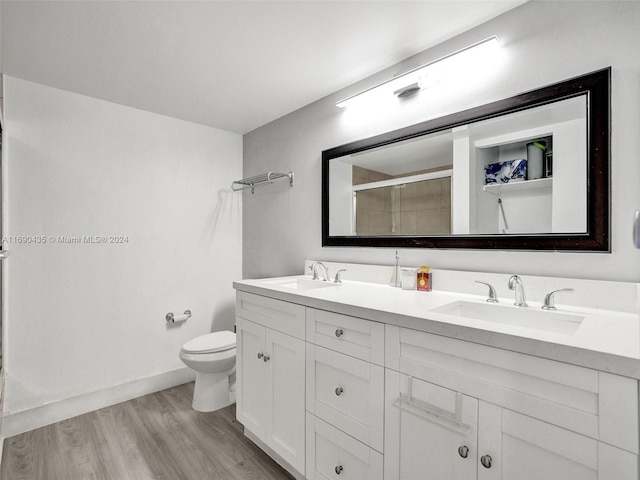 bathroom with hardwood / wood-style floors, vanity, toilet, and a shower