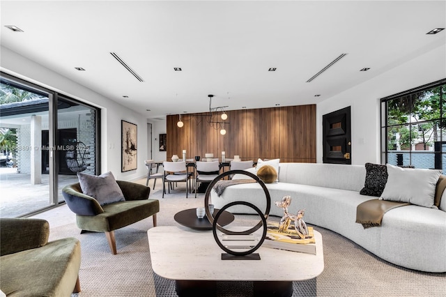 living room with wood walls, an accent wall, visible vents, and light colored carpet