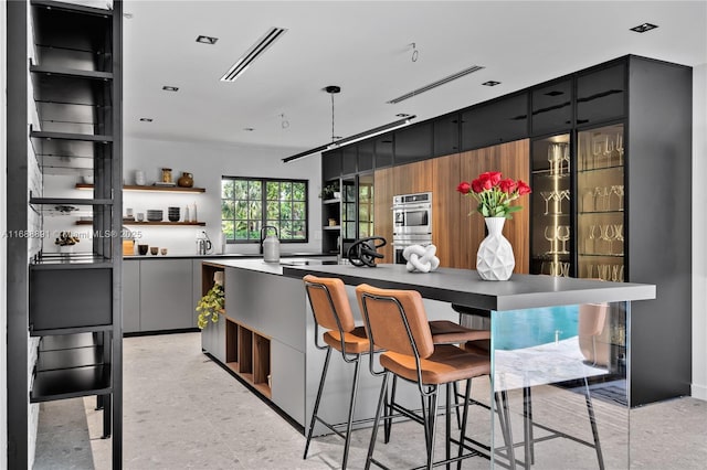 interior space featuring a breakfast bar, open shelves, visible vents, double oven, and modern cabinets