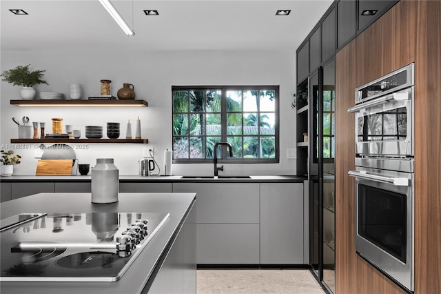 kitchen with modern cabinets, black electric stovetop, double oven, open shelves, and a sink